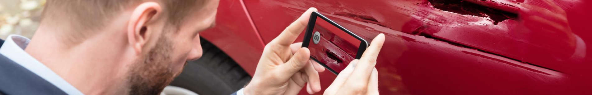 Car owner takes photo of damaged car with smartphone.